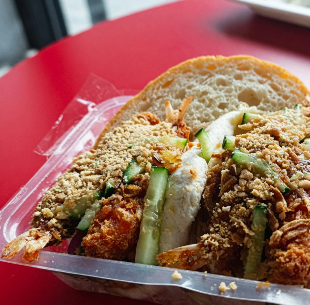 Gros plan sur deux bánh mì croustillants au poulet pané, concombre et oignons rouges